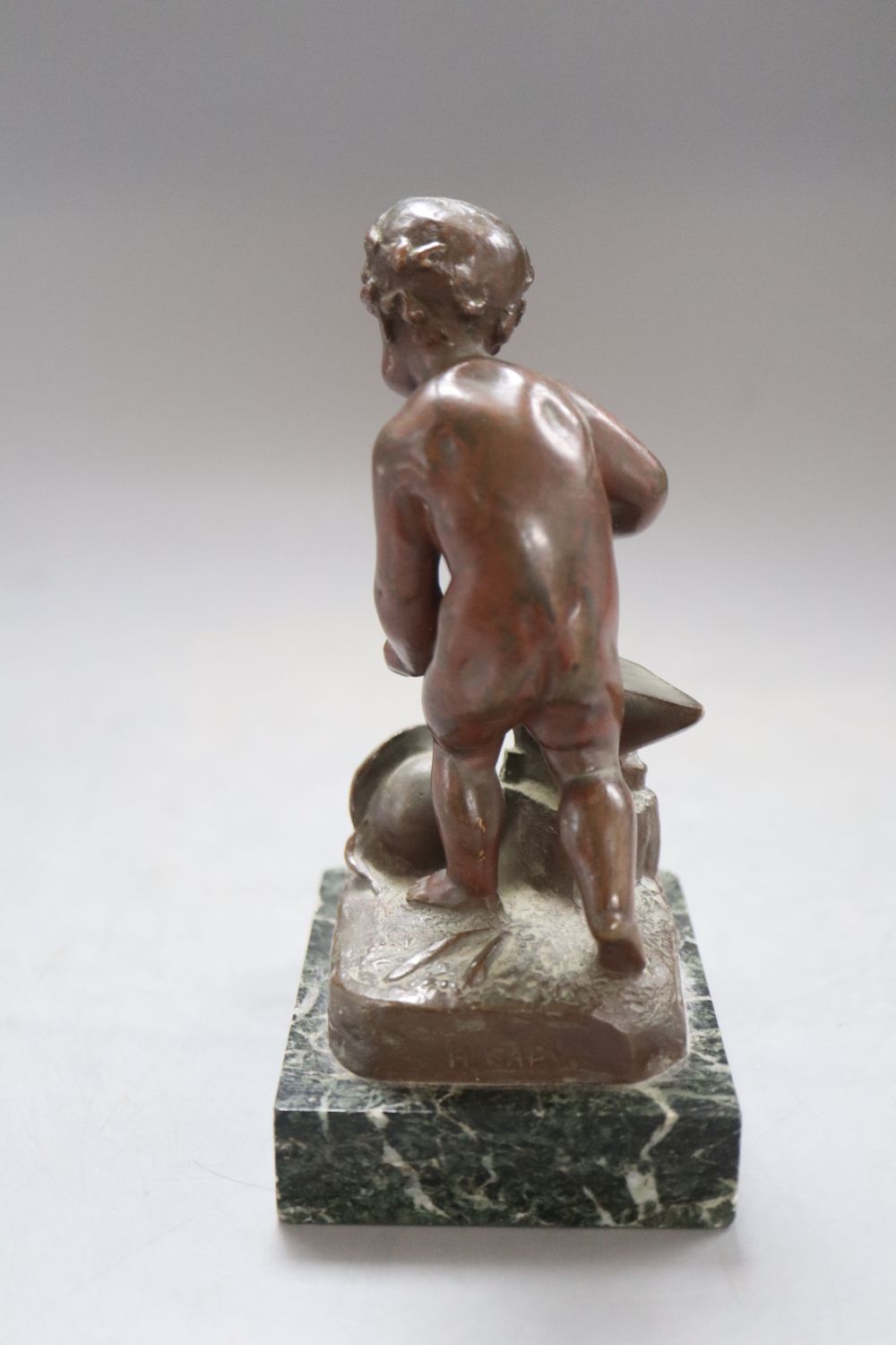 A bronze putto blacksmith, signed H. Capy, on marble base, height 15cm